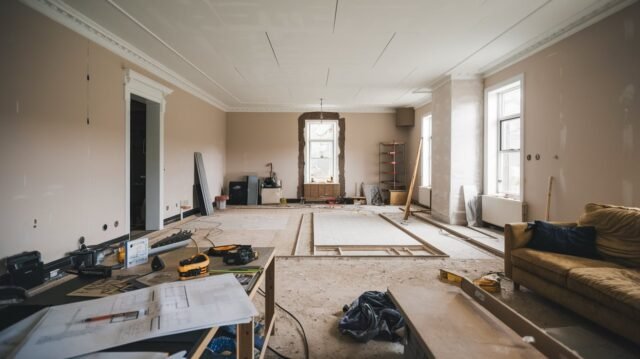 Living room under refurbishment with tools, plans, and fresh paint showcasing a home renovation in progress.